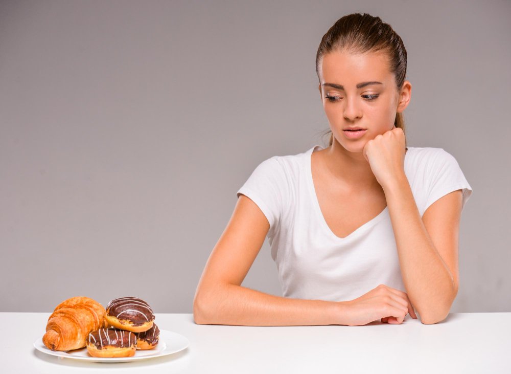 Mujer contemplando dulces en una dieta baja en carbohidratos.
